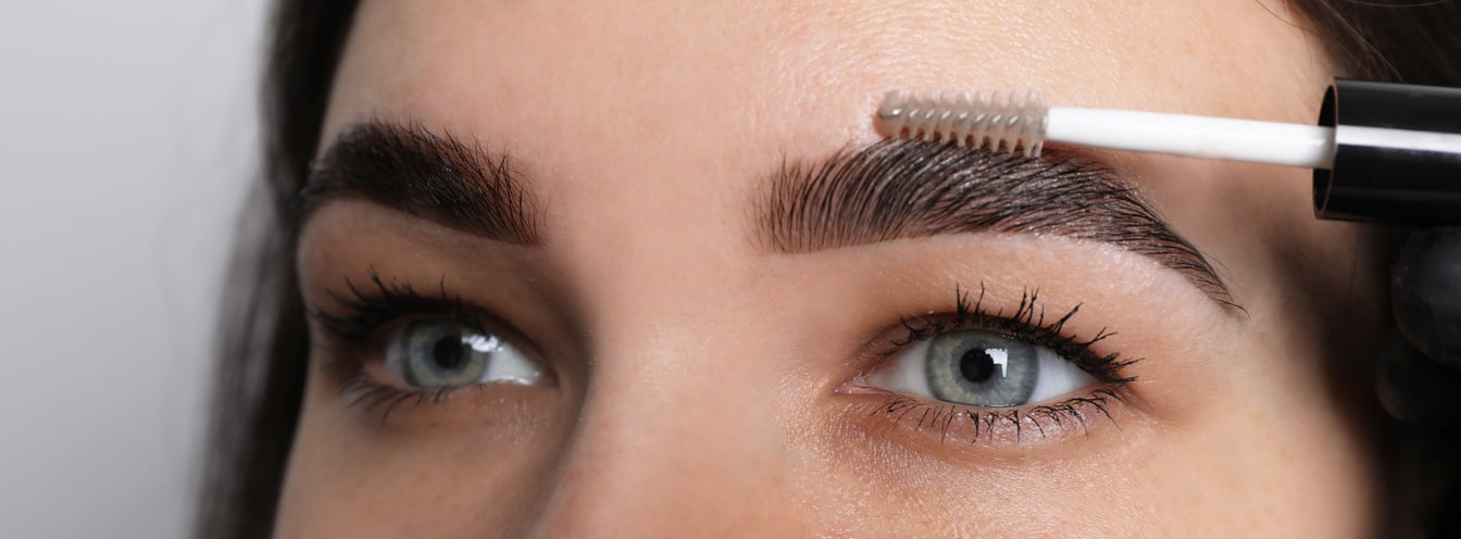 Beautician Fixing Woman's Eyebrows with Gel after Tinting on Lig